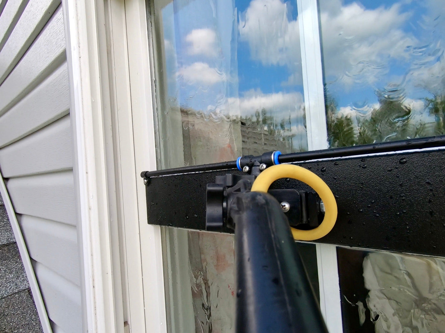 Battlecat Scrubber cleaning a window with rinse bar rinsing the glass. The up and down pivot is great for keeping the scrubber flat against the glass for full contact at all times.