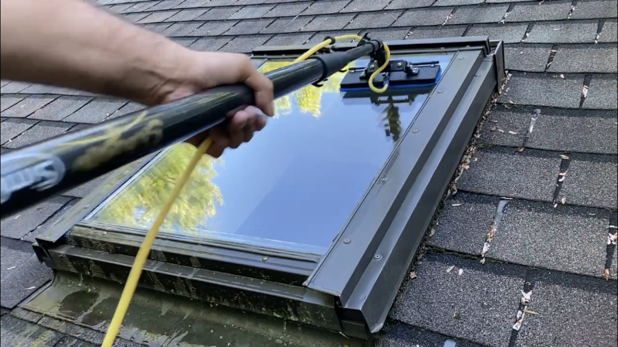 Cleaning sky light with water fed pole and scrubber. Professional window cleaner using blue and white scrubbing pads. Scrubber has rinse bar and swivel gooseneck. 